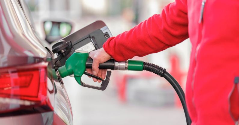 Car Ownership - Closeup of man pumping gasoline fuel in car at gas station