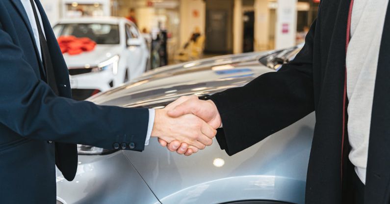 Car Deal - Close up of Men Shaking Hands and Cars in Background