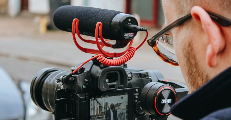 Stability Control - Crop anonymous professional videographer recording video on camera on street