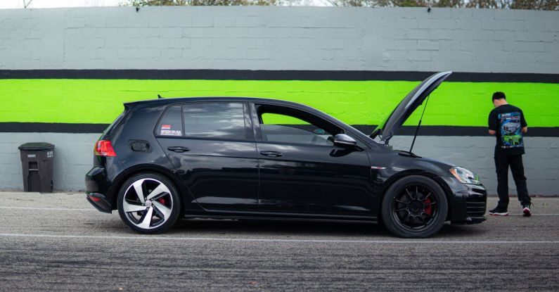 Volkswagen ID.4 - A black golf r is parked in front of a green wall